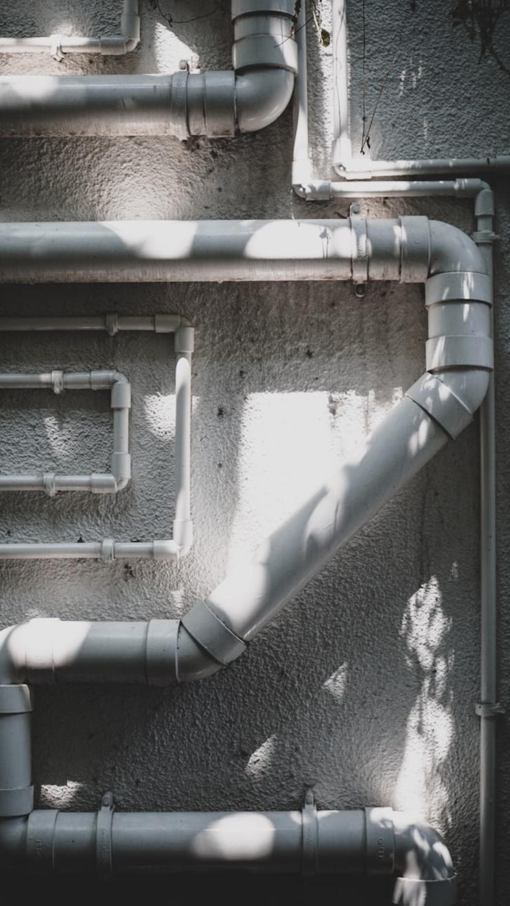 A cleaning device with a mop head is applying a soapy solution to a textured gray tile floor.